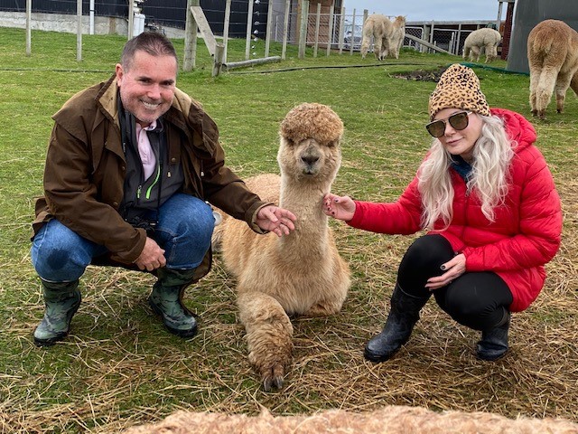 Shawn and her husband kneel by a llama