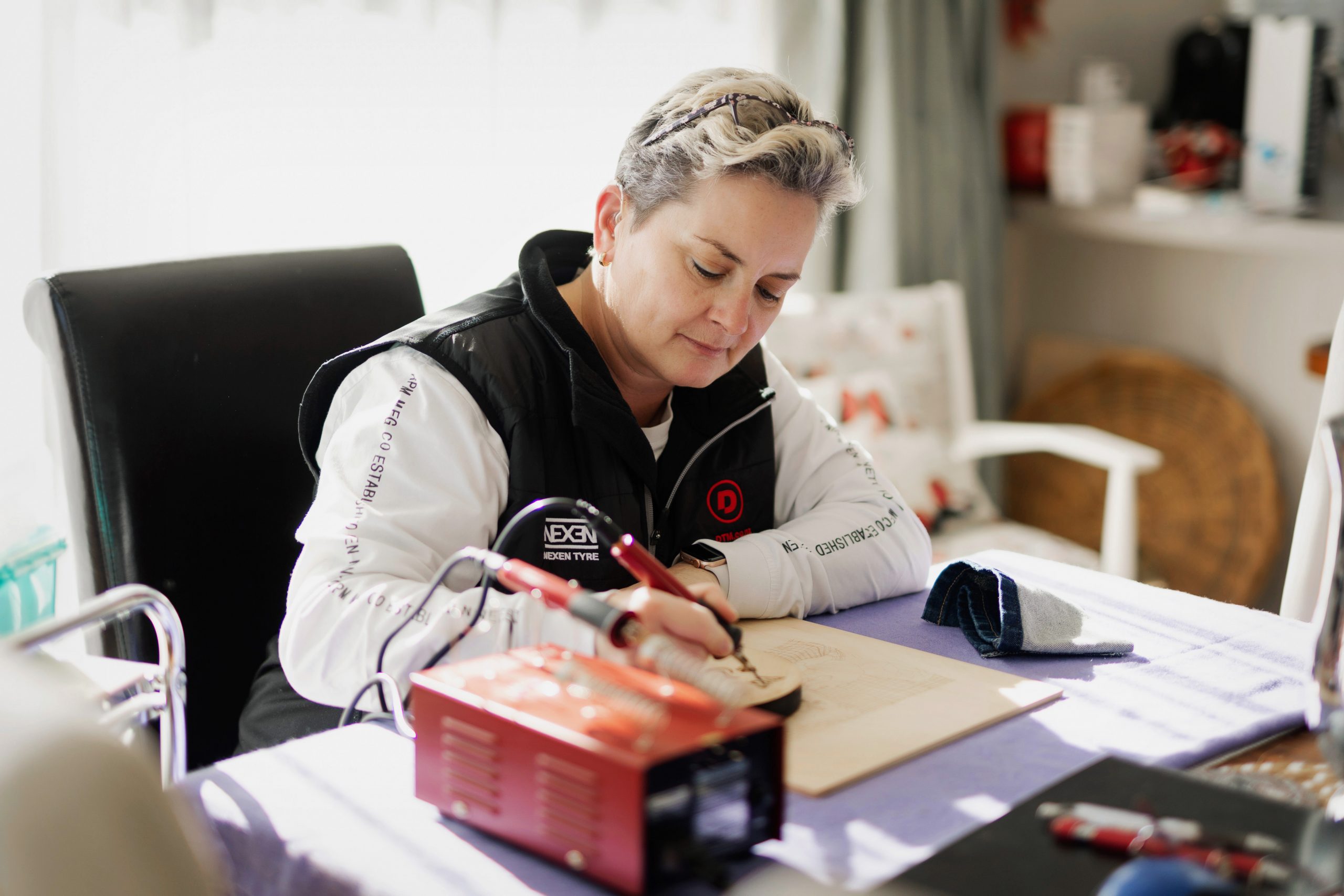 Lianna sits at a table in her house, concentrating hard on an art project in front of her.