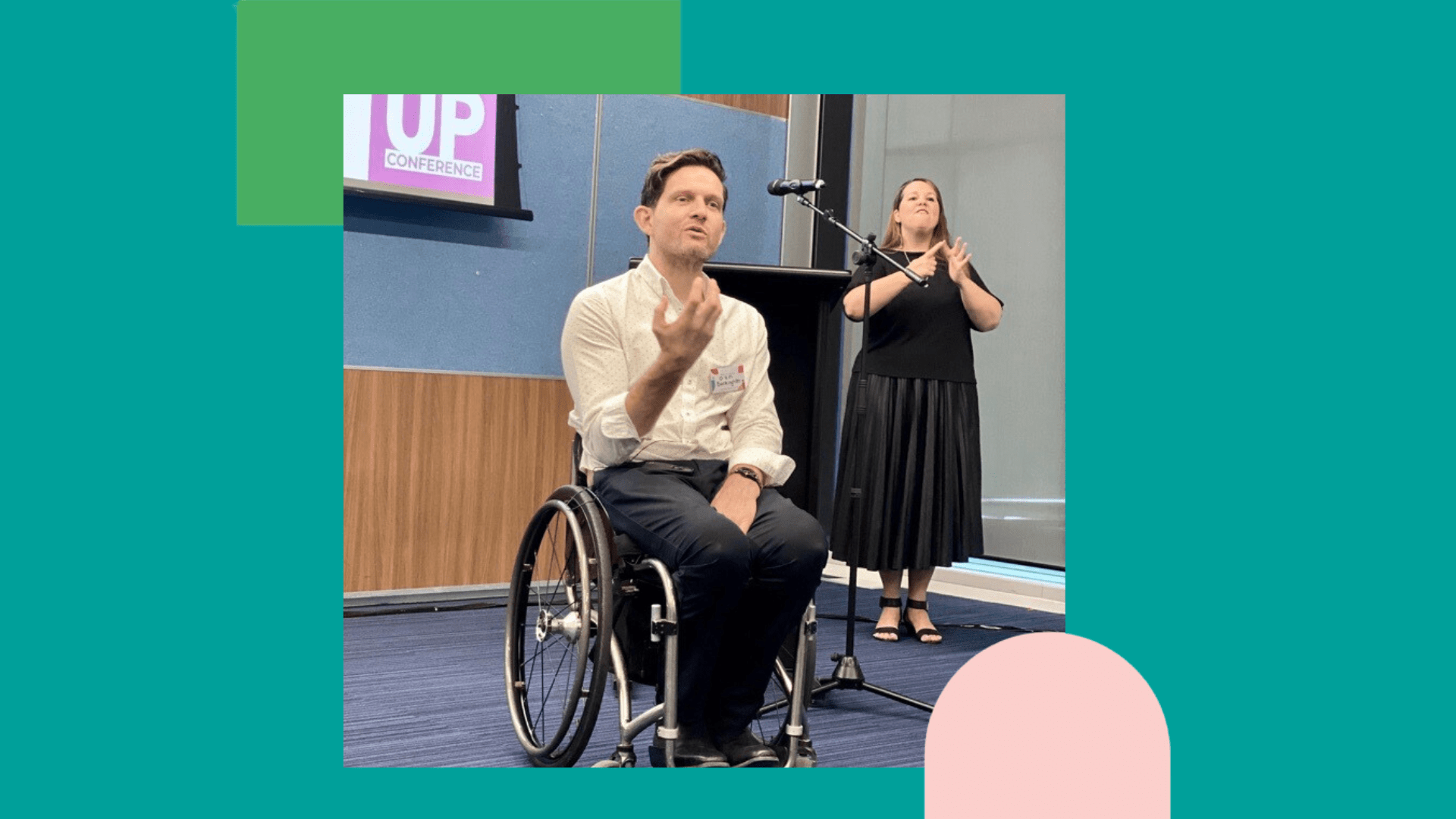 Image of Able Chief Executive Dan Buckingham speaking at the Listen Up conference. Standing behind him is NZSL interpreter Kelley Hodgins translating his presentation.